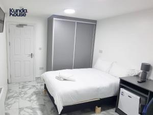 een slaapkamer met een wit bed en een televisie bij Elegant Ensuite Rooms Near City Centre - Kunda House in Birmingham