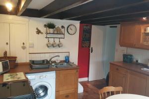 a kitchen with a washing machine and a sink at Isallt Cosy Cottage. Dogs Welcome. Superking & Double Bed. Log Burner. Peaceful Village Location in Llanbrynmair