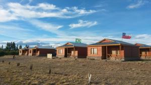 una fila de casas en un campo con banderas en Cabañas Palo Blanco en Gobernador Costa