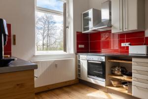 una cocina con azulejos rojos en las paredes y una ventana en Zeitreise: Wohnen im Herrenhaus genau zw. L u. DD, en Mügeln