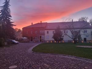 uma casa com uma entrada de tijolos em frente a um pôr-do-sol em Zeitreise: Wohnen im Herrenhaus genau zw. L u. DD em Mügeln