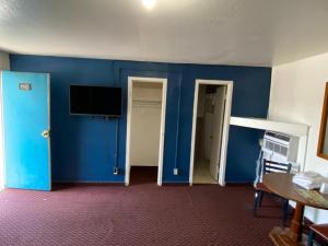 a room with blue walls and a table and a tv at Western inn in Tulsa