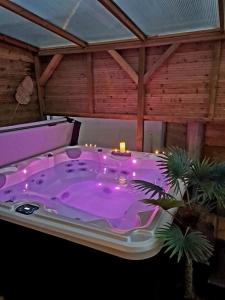 a purple bath tub with candles in a room at A Fleur de Spa : Maison chaleureuse avec spa privatif et billard. in Coulogne