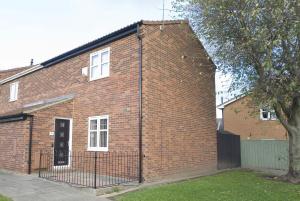 a red brick building with a black gate at Marlborough Cottage in Stockton-on-Tees