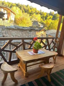 une table en bois avec une plante en pot sur une terrasse dans l'établissement Къща за гости Близнаците, à Leshten