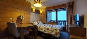 een slaapkamer met een bed, een bureau en een televisie bij Lune D'Argent Appartement avec vue sur la montagne in Megève