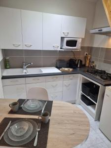 a kitchen with white cabinets and a wooden table at Le Vivien in Romorantin