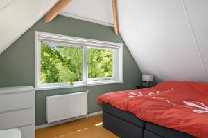 1 dormitorio con cama roja y ventana en Boshuisje, en Olst