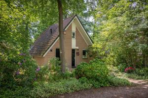 una pequeña casa rodeada de árboles y flores en Boshuisje, en Olst