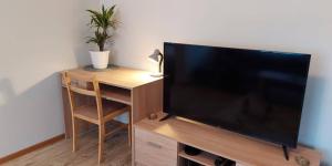 una TV a schermo piatto seduta su un supporto in legno con sedia di Pelguranna Apartment a Tallinn
