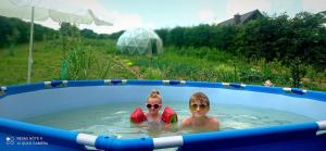 two people are swimming in a swimming pool at Domek Regionalny- bliźniak in Baligród