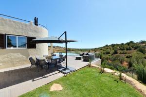 a patio with a table and an umbrella on the grass at Tower Villa w Infinity Pool in Olhão