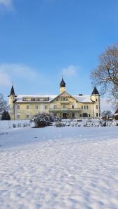 a large yellow building with snow in front of it at Gästehaus Gut Frauendorf in Windorf