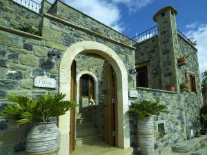 une entrée à un bâtiment en pierre avec deux plantes en pot dans l'établissement Diktynna Traditional Villas, à Anatolí