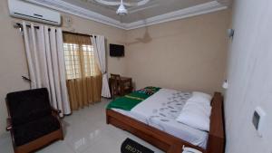 1 dormitorio con 1 cama y 1 silla en Bois vert Hôtel, en Abomey