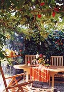 een schilderij van een tafel en stoelen onder een boom bij Haus mit Lilie und Rose in Westerdeichstrich