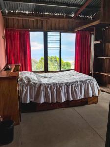 una camera con letto in una stanza con tende rosse di Hospedaje Coffee Mountain a San Isidro