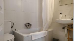 a bathroom with a tub and a sink and a toilet at Pension Alver in Cudillero