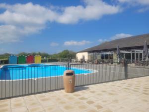 a fence around a swimming pool with a trash can at Primrose - 3 bedroom luxury lodge in South Cerney