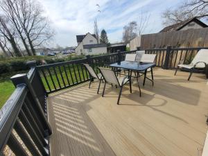 a deck with a table and chairs and a fence at Primrose - 3 bedroom luxury lodge in South Cerney