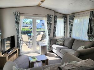 a living room with a couch and a tv at Primrose - 3 bedroom luxury lodge in South Cerney