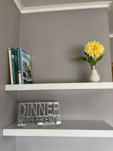 un estante con un jarrón con una flor amarilla y libros en Appartement29 en Wetteren