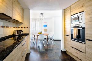 una cocina con armarios de madera y una mesa con sillas. en Villa Vidal en San Jose de sa Talaia