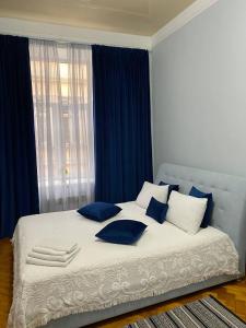 ein Bett mit blauen und weißen Kissen und einem Fenster in der Unterkunft Centr Opera House 2 rooms in Lwiw