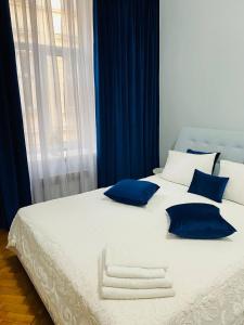 ein großes weißes Bett mit blauen Kissen und einem Fenster in der Unterkunft Centr Opera House 2 rooms in Lwiw