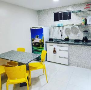 une cuisine avec une table à manger et des chaises jaunes dans l'établissement Atlântico Flat - Apto 004, à Natal