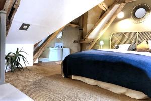 ein Schlafzimmer mit einem großen blauen Bett im Dachgeschoss in der Unterkunft NATIFRIENDLY-Appartement centre historique avec jardin IDEAL FAMILLE in Bellême
