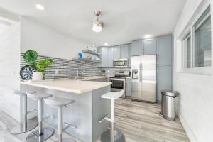 una cocina con electrodomésticos de acero inoxidable y armarios blancos en Modern Miami Home 10 Min to the AIRPORT L03 en Miami