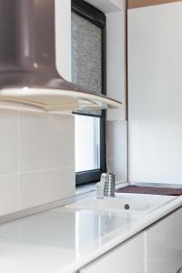a white kitchen with a sink and a window at Luxury Apartment with Private Parking in Giroc