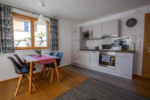 a kitchen with white cabinets and a table and chairs at Ferienwohnung Wallner in Wald am Arlberg