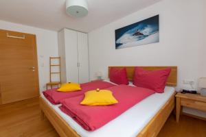 a bedroom with a large bed with red and yellow pillows at Ferienwohnung Wallner in Wald am Arlberg