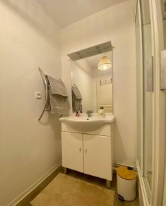 a white bathroom with a sink and a mirror at Superbe Appartement cosy et calme avec un parking in Corbeil-Essonnes