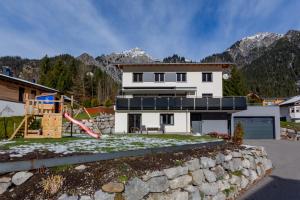a large white house with a rock wall at Ferienwohnung Wallner in Wald am Arlberg