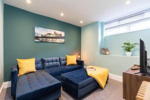 a living room with a blue couch and a tv at The Bakery A Renovated Gem in Central Brighton in Brighton & Hove
