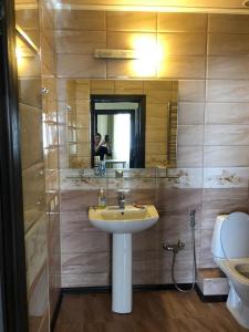 een badkamer met een wastafel, een toilet en een spiegel bij Квартира в центре Бишкека! in Bisjkek