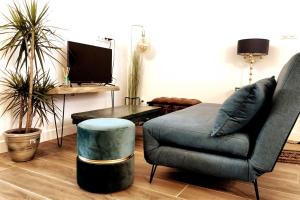 een woonkamer met een bank, een stoel en een tv bij NATICOSY-Appartement centre historique avec jardin IDEAL COUPLE in Bellême