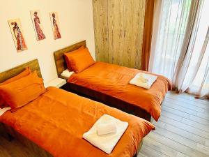 duas camas num quarto com lençóis laranja em Genius Loci em Kavala