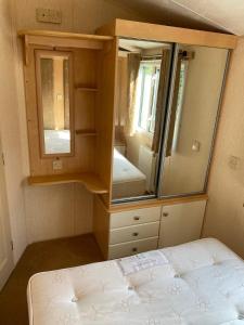 een kleine slaapkamer met een bed en een spiegel bij Summerlands, Ingoldmells 8 berth caravan in Skegness