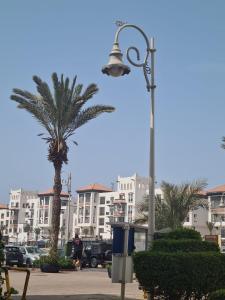 a street light with a palm tree and buildings at mArinAr in Agadir