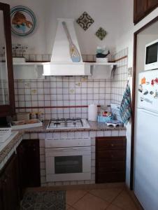 a kitchen with a stove and a white refrigerator at VILLA CORALLINA in San Vito lo Capo