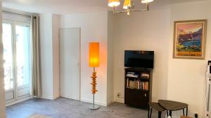 een woonkamer met een vloerlamp en een tv bij Résidence Poste & Golf, appartement pour 4 personnes au cœur de Luchon in Luchon
