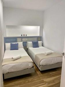 a room with two beds with blue pillows at VELALMA DÚPLEX centro histórico in Jaén