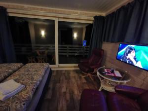 um quarto com uma cama, uma televisão e um sofá em Utsikten em Gjesvær