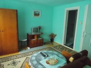 a living room with a table and a television at Pensiunea Ibolya in Băile Tuşnad