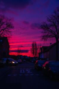 弗勒爾斯海姆的住宿－House Elinor Suite，紫色和红色的天空,停车场有车辆停放