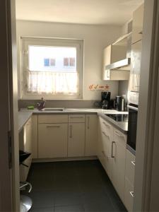 a kitchen with white cabinets and a window and a sink at House Elinor Suite in Flörsheim am Main